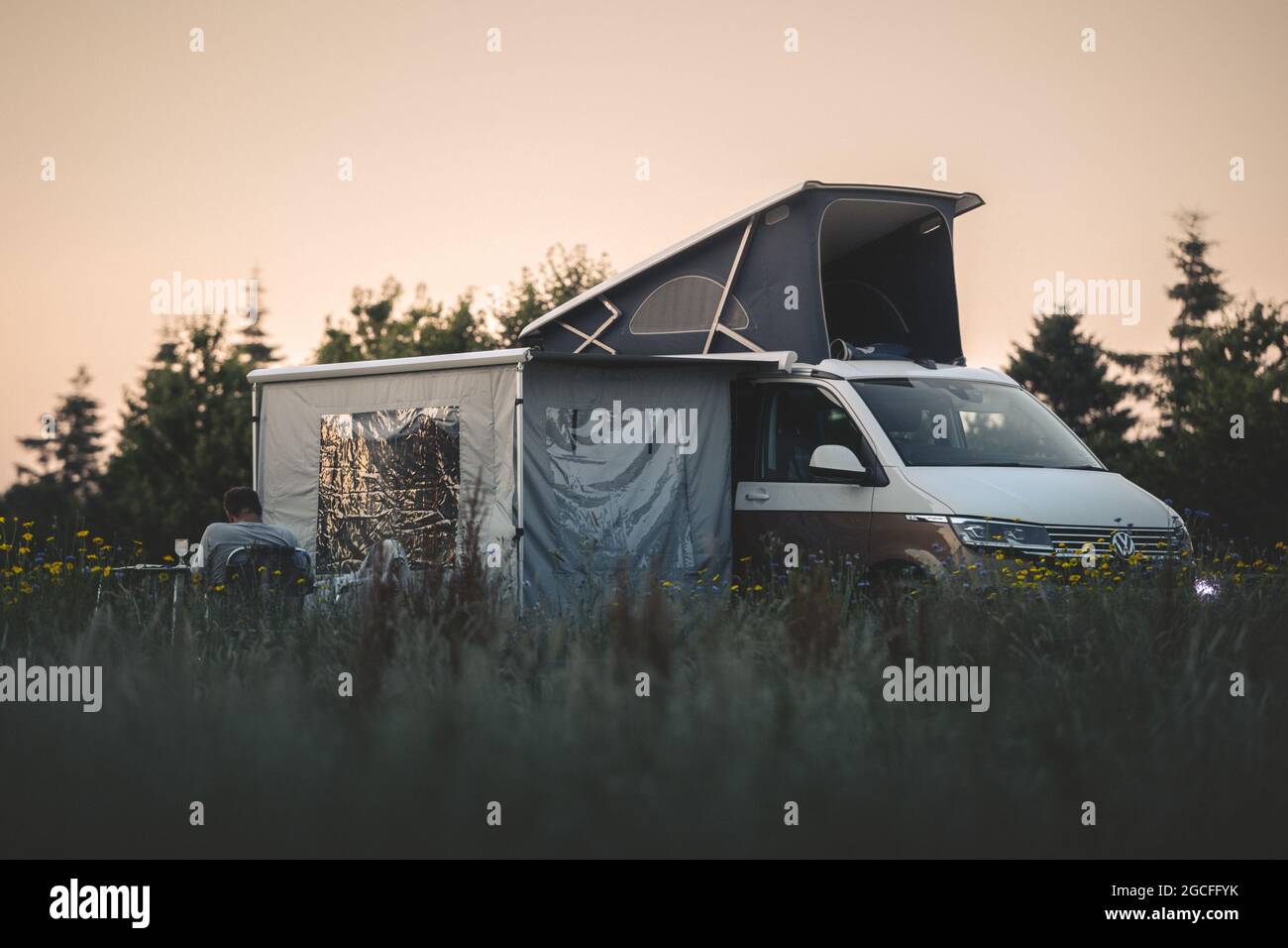 Chester, Cheshire - 17. Juli 2021: Ein VW-Campingbus wurde zum Campen mit einem Mann verwendet, der beim Zelten bei Sonnenuntergang Wein trinkt Stockfoto