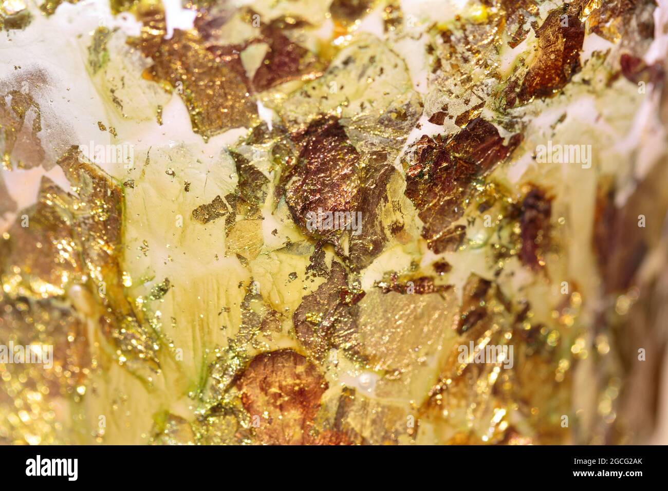 Abstrakter Hintergrund aus verstreuten, funkelnden, schimmernden Goldflecken, Gelb, Bernstein, Kupfer und Weiß mit geringer Schärfentiefe Stockfoto