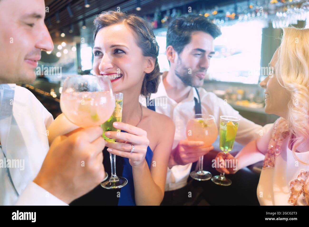 Frauen und Männer am Tresen einer Bar ihre Drinks genießen Stockfoto