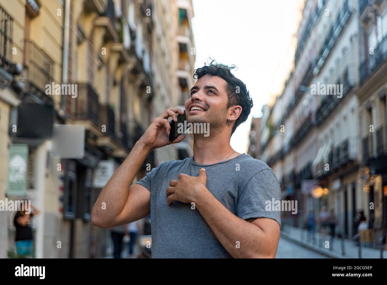 Junger latein in der Stadt, der mit dem Handy spricht. Stockfoto