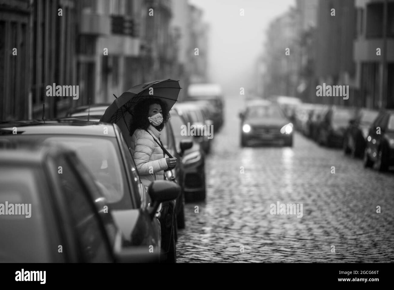Asiatische Frau in antiviraler Maske auf der Straße bei bewölktem Wetter. Schwarzweiß-Foto. Stockfoto