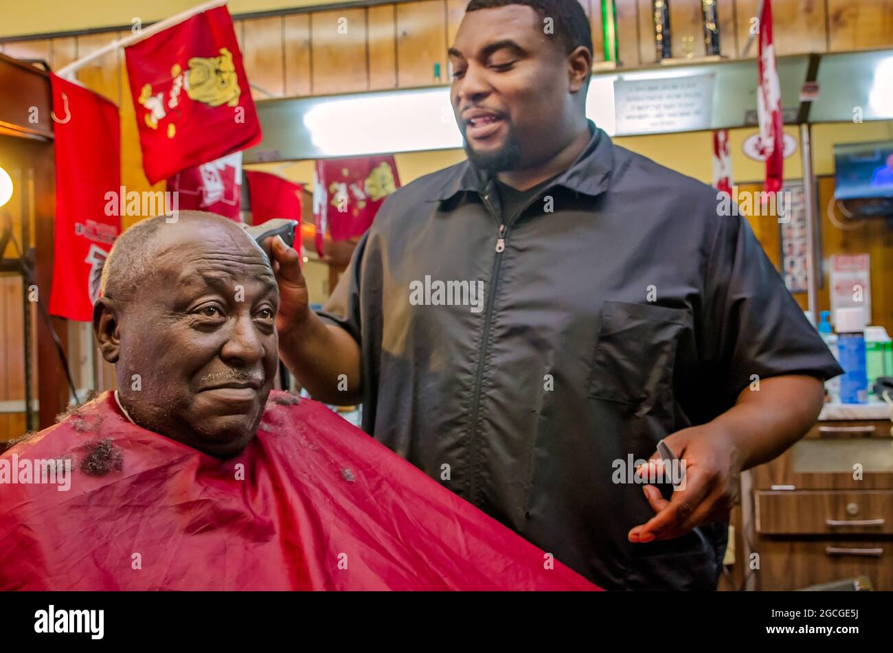 Ein Friseur spricht mit seinem Kunden, während er bei Gibsons Hair Styles and Cuts am 23. April 2013 in West Point, Mississippi, Haare schneidet. Die Einheimischen sagen, dass Arbeitsplätze nötig sind Stockfoto