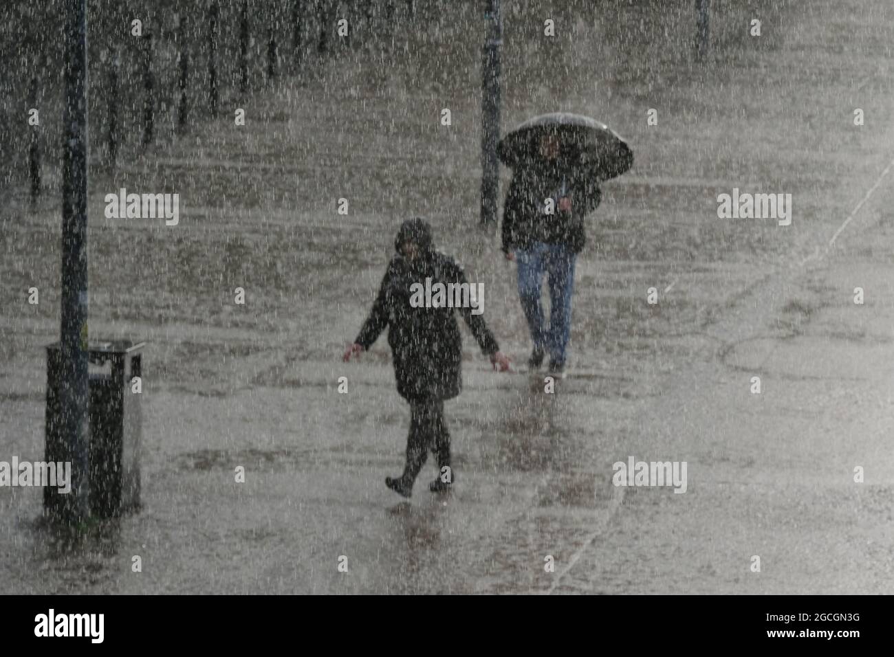 London, Großbritannien. Zwei Menschen beeilen sich bei sintflutartigen Regenfällen entlang der Southbank, während das unruhige Wetter anhält. Stockfoto