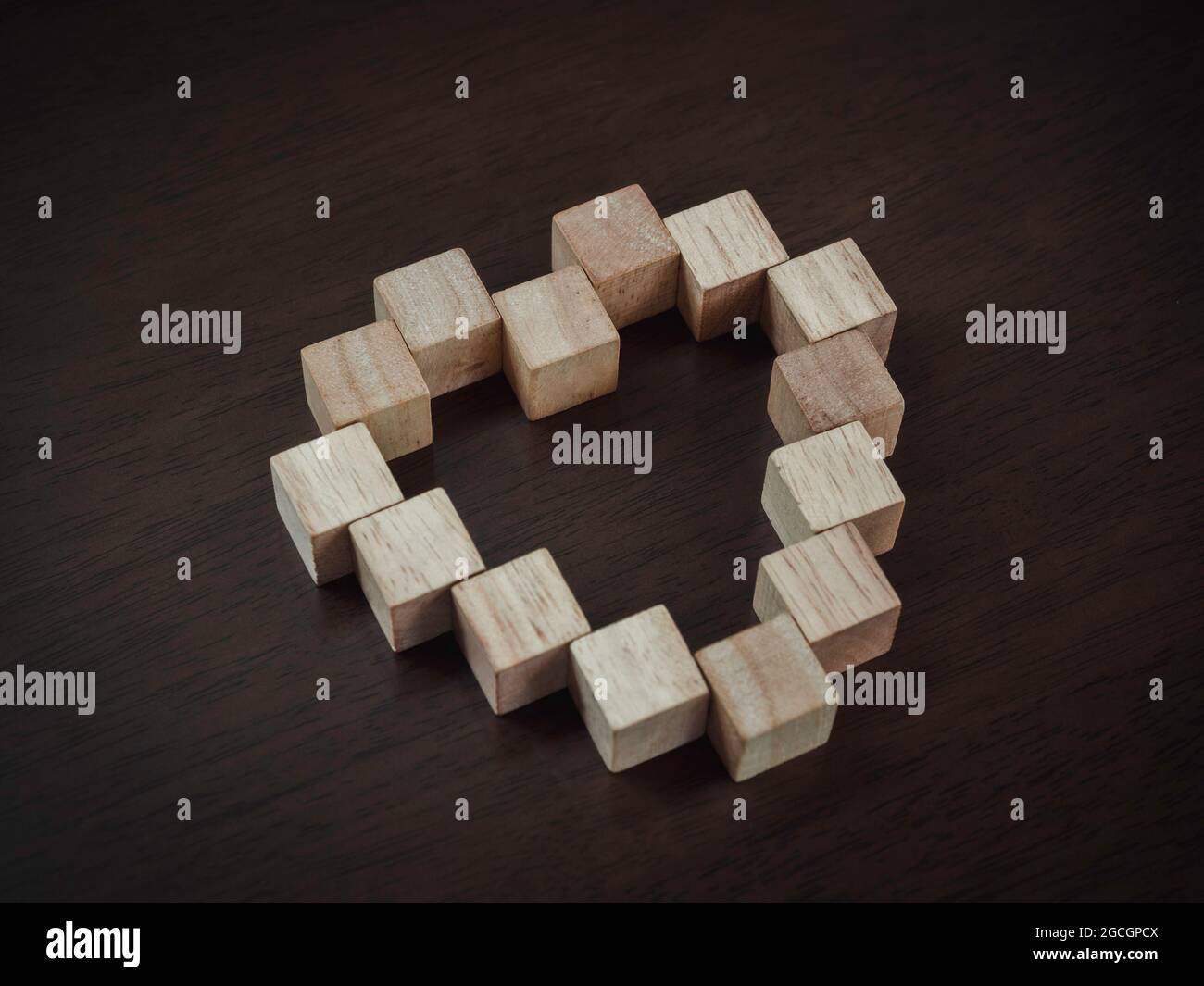 Holzblöcke in Herzform auf dunklem Holzhintergrund angeordnet, Draufsicht. Liebe und Koexistenz Konzept. Stockfoto