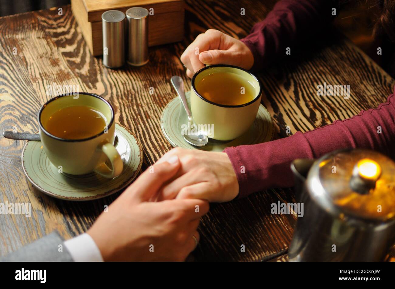 Nahaufnahme eines jungen Paares, das in einem Café die Hände hält und Tee trinkt. Romantische Zeit Stockfoto