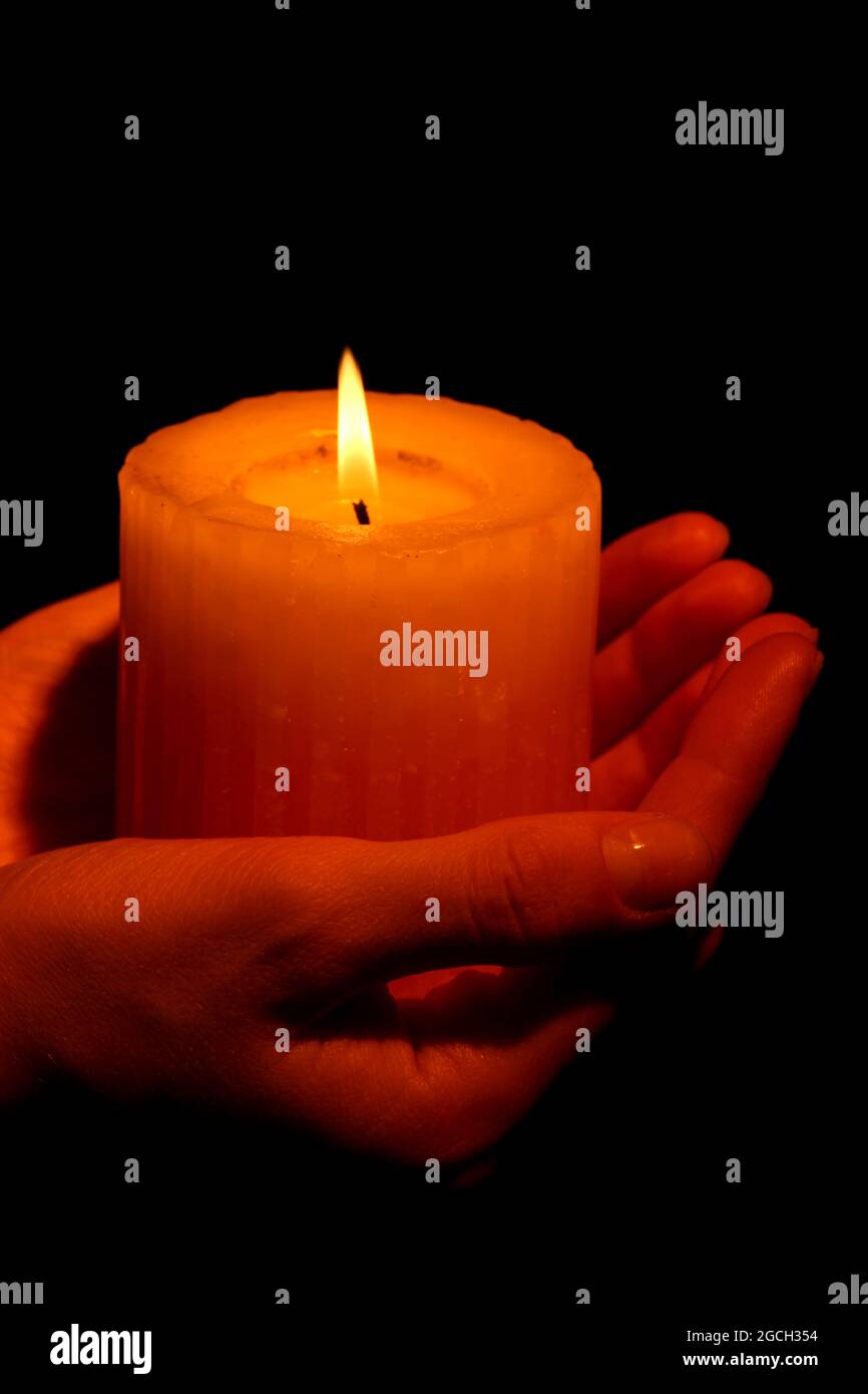 Brennende Kerze in der Hand auf Schwarz isoliert Stockfotografie - Alamy