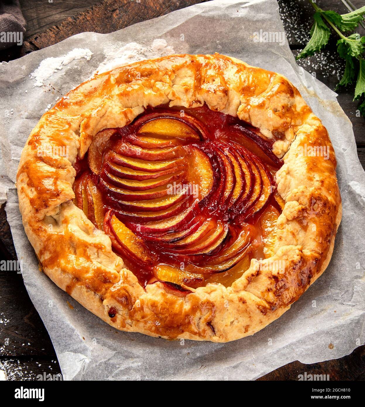 Pfirsich-Gallete auf Backpapier auf Holzhintergrund. Frisch zubereiteter hausgemachter Kuchen. Draufsicht, flach liegend Stockfoto