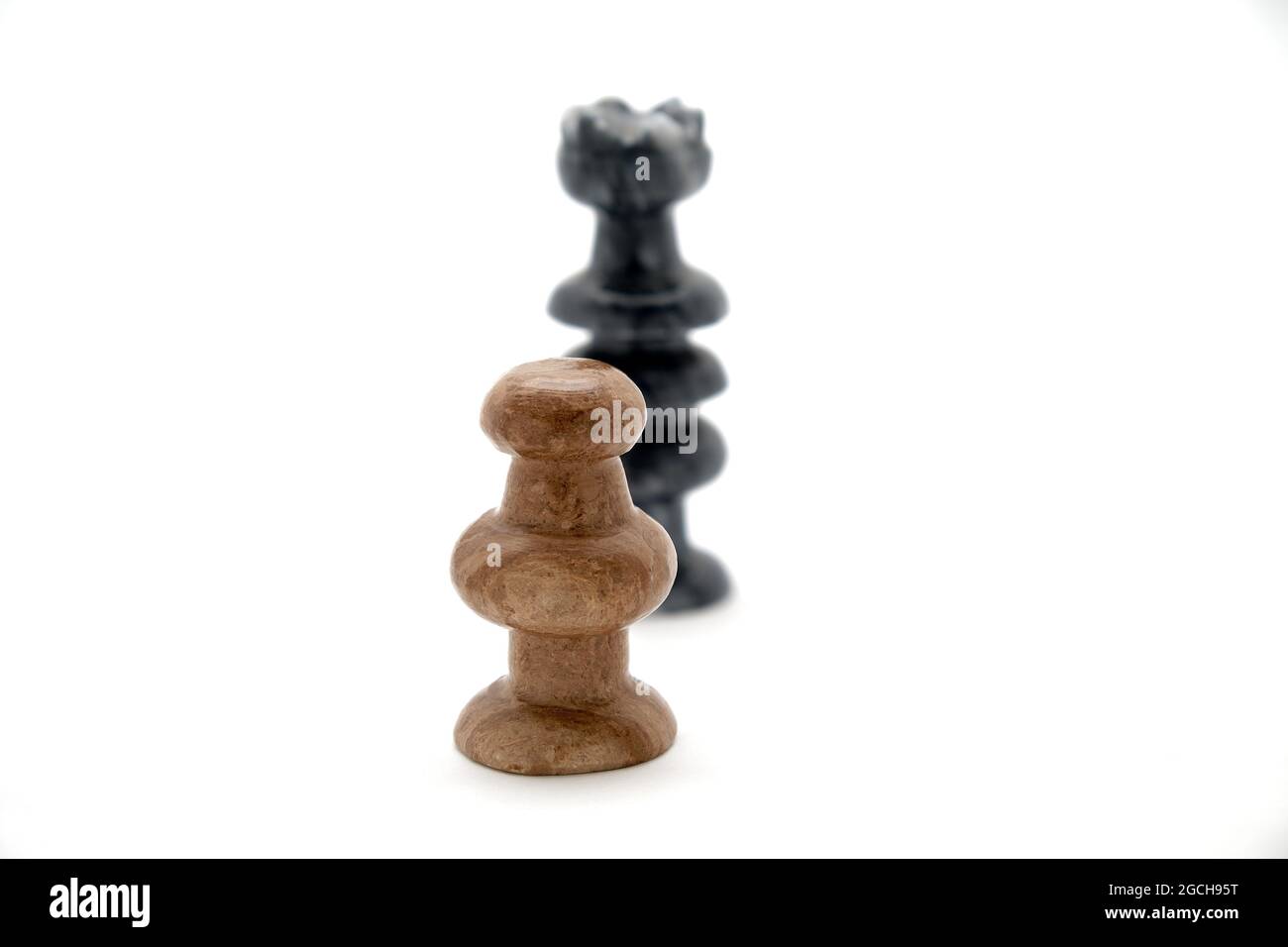 Zwei Schachfiguren, weiße Spielfigur und schwarze Königin stehen offen Stockfoto