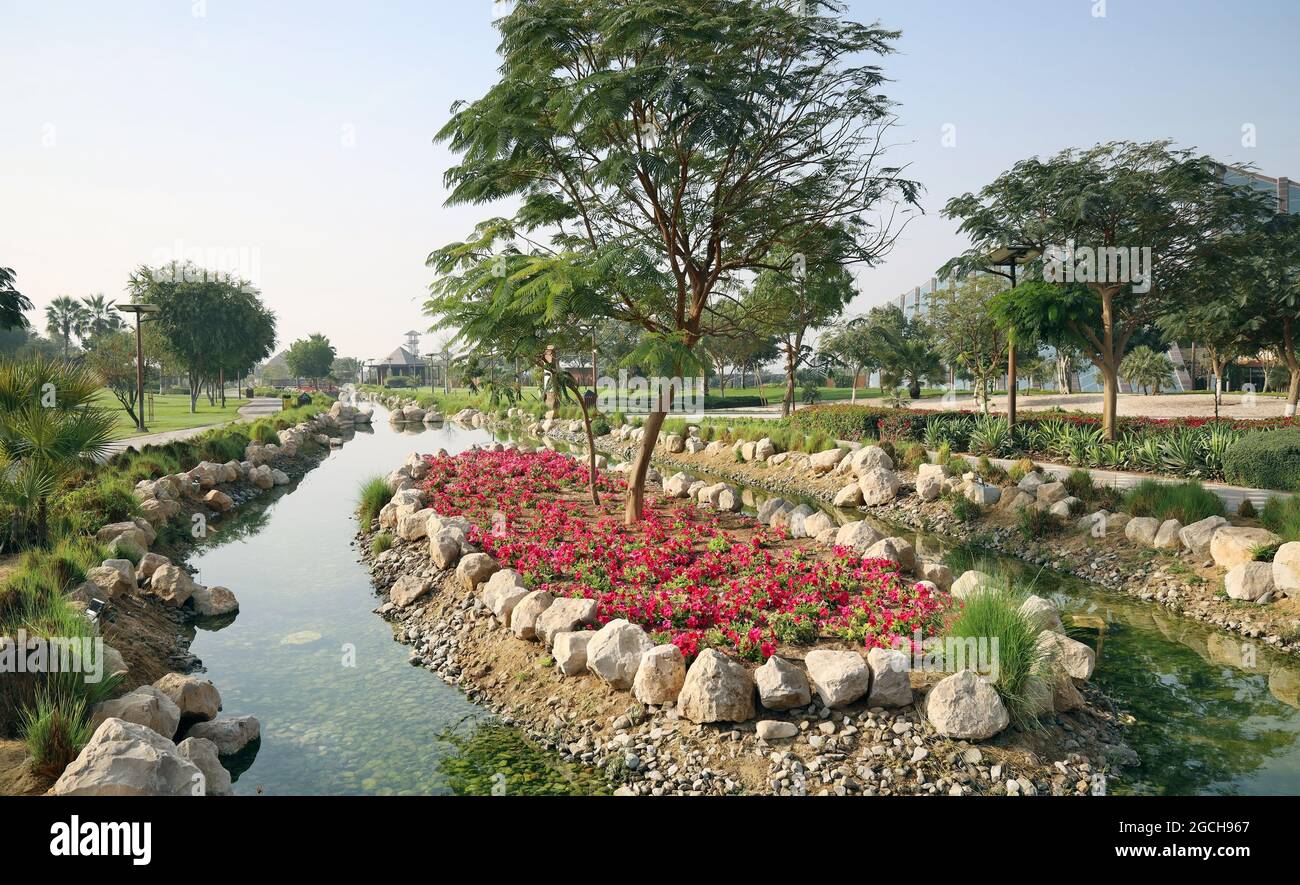 Der öffentliche Stadtpark ist mit großen Steinen und Blumenbeeten mit roten Blumen geschmückt Stockfoto