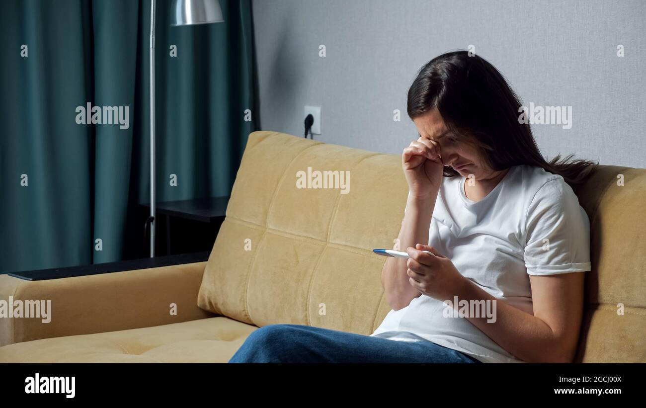 Junge Frau mit Frustration schaut auf Schwangerschaftstest Stockfoto