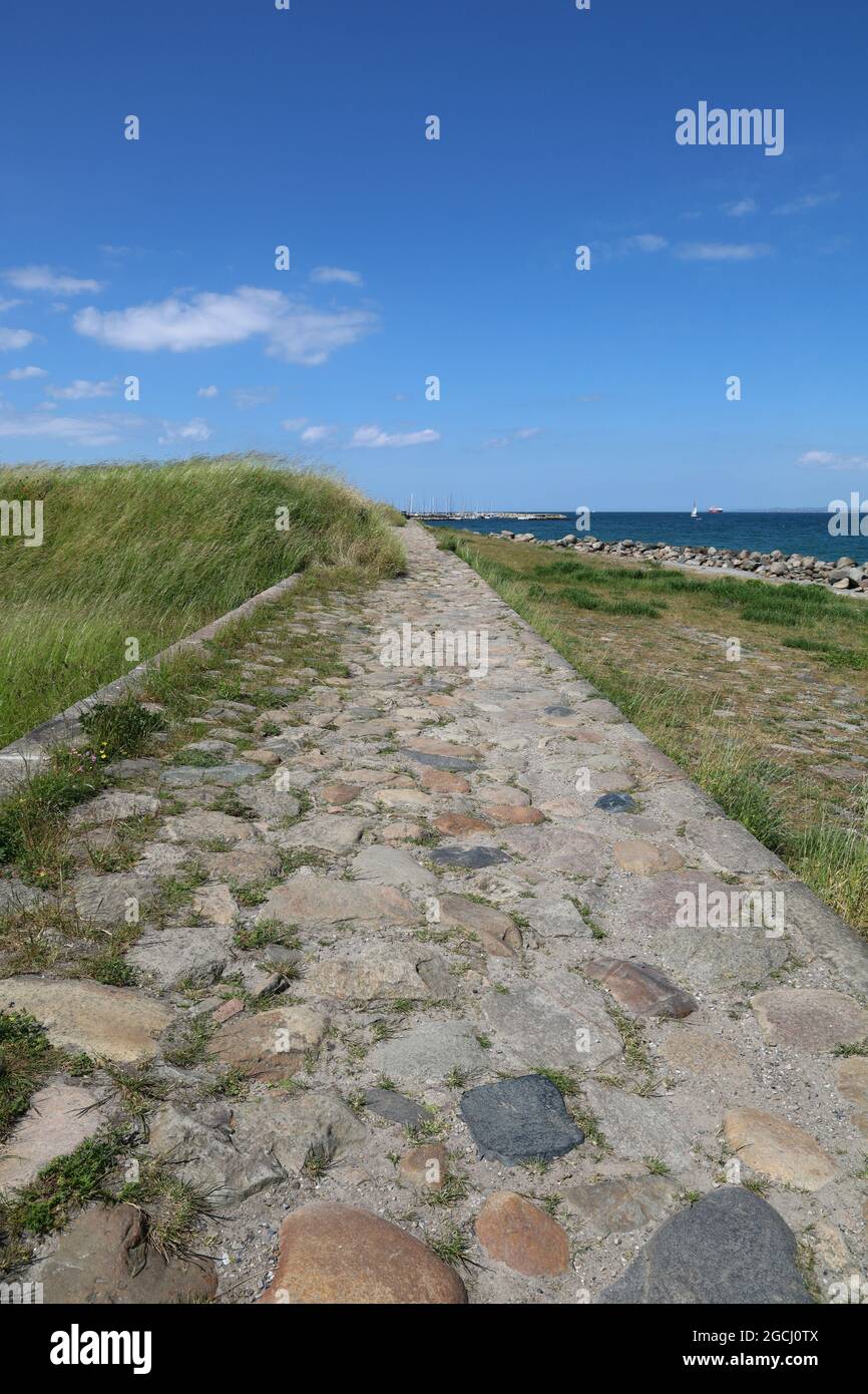 Kopfsteinpflaster-Gehweg entlang des leeren Rageleje-Strandes in Dänemark Stockfoto