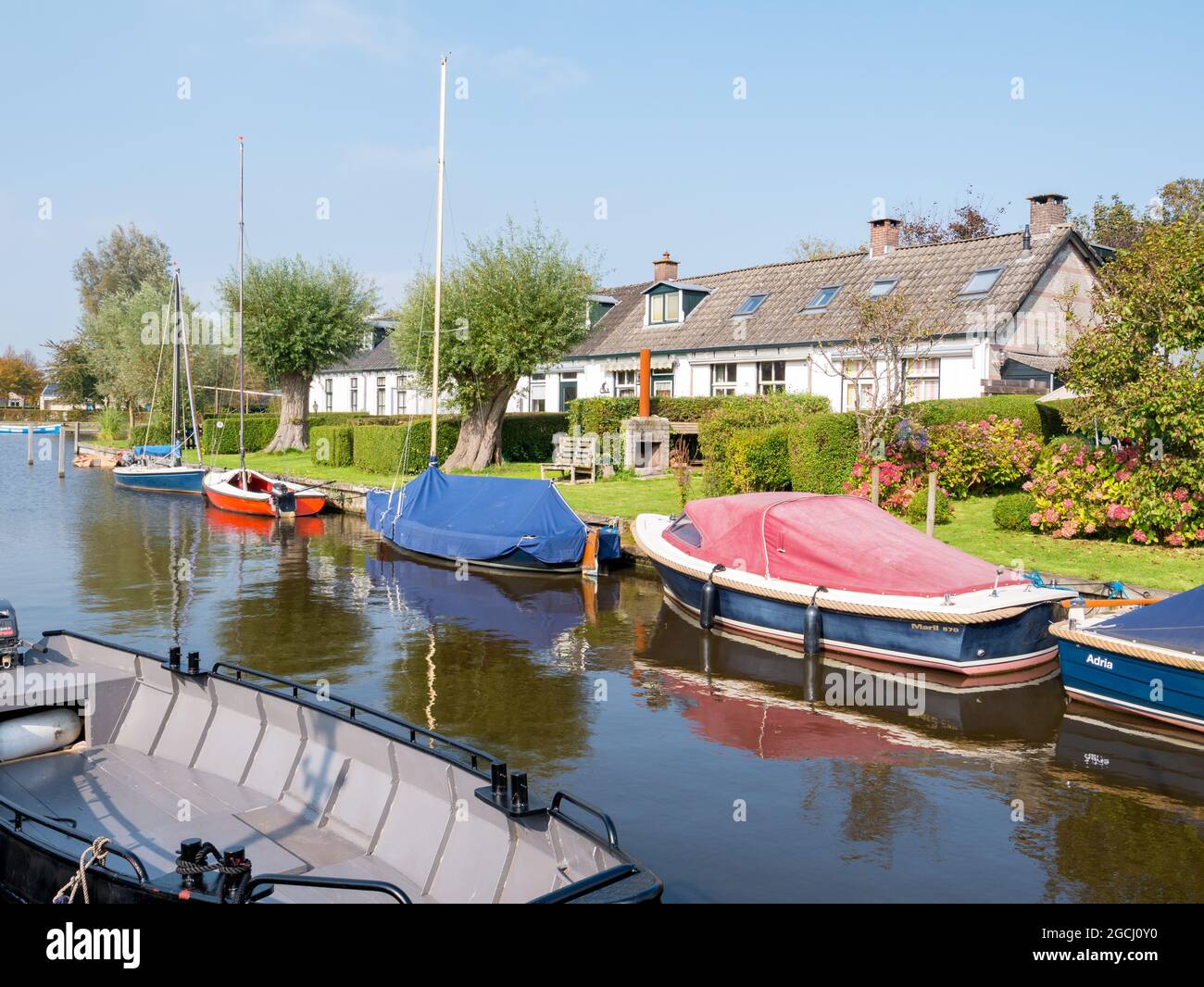 Boote in Kanal und Häuser in Dorf Langweer, Friesland, Niederlande Stockfoto