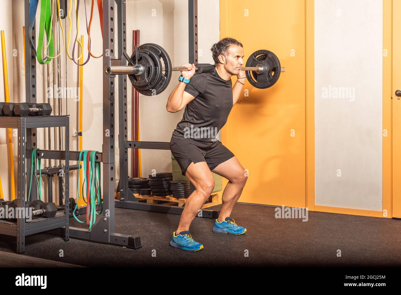 Sportler erwachsener Mann macht Kniebeugen mit Bar im Fitnessstudio Stockfoto