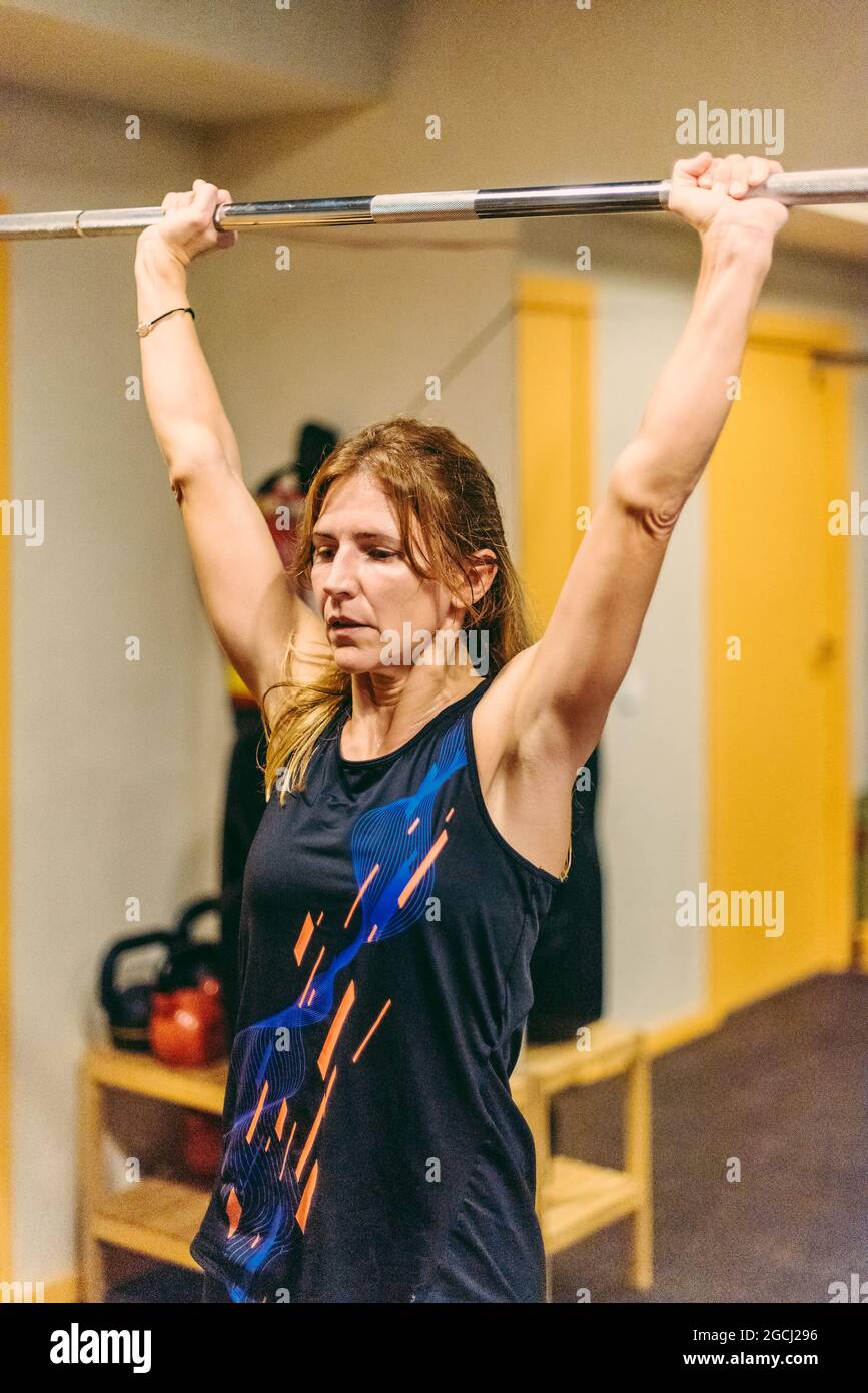 Athletin Frau macht Presseübungen mit Bar im Fitnessstudio Stockfoto