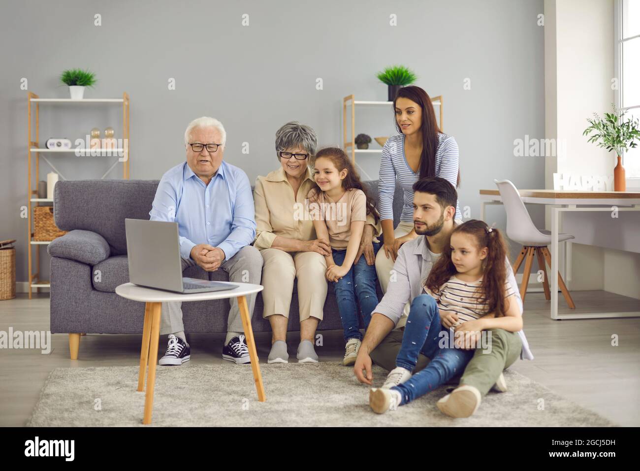 Eine große, freundliche Familie traf sich zu Hause im Wohnzimmer, um einen Film auf einem Laptop anzusehen. Stockfoto