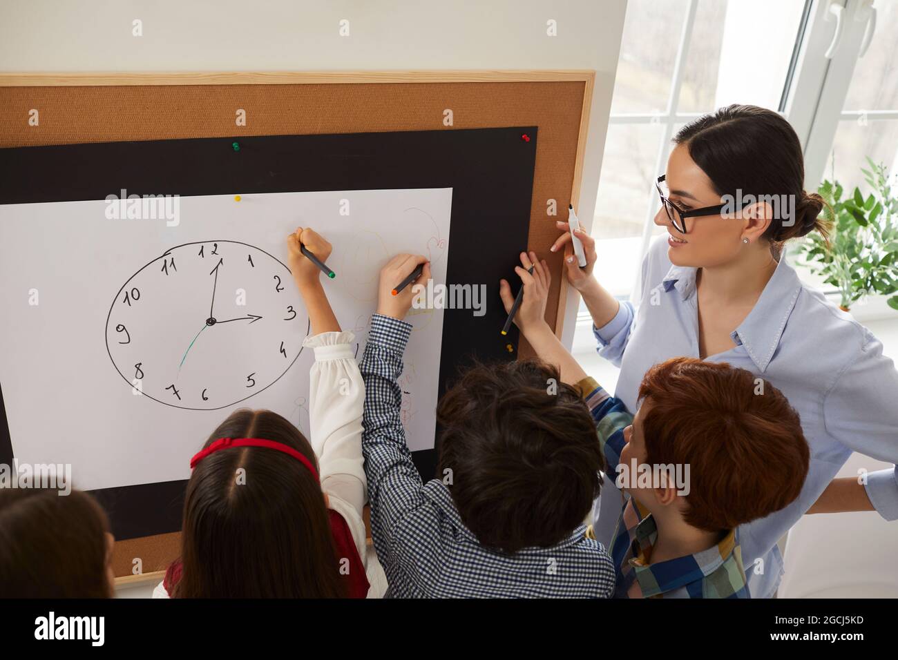 Gruppe von Grundschülern, die eine Uhr zeichnen und lernen, die Zeit zu sagen Stockfoto
