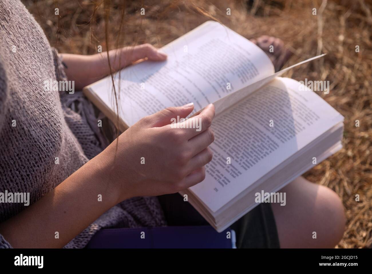 Junge Frau mit Buch beim Sitzen im Freien, Nahaufnahme Stockfoto