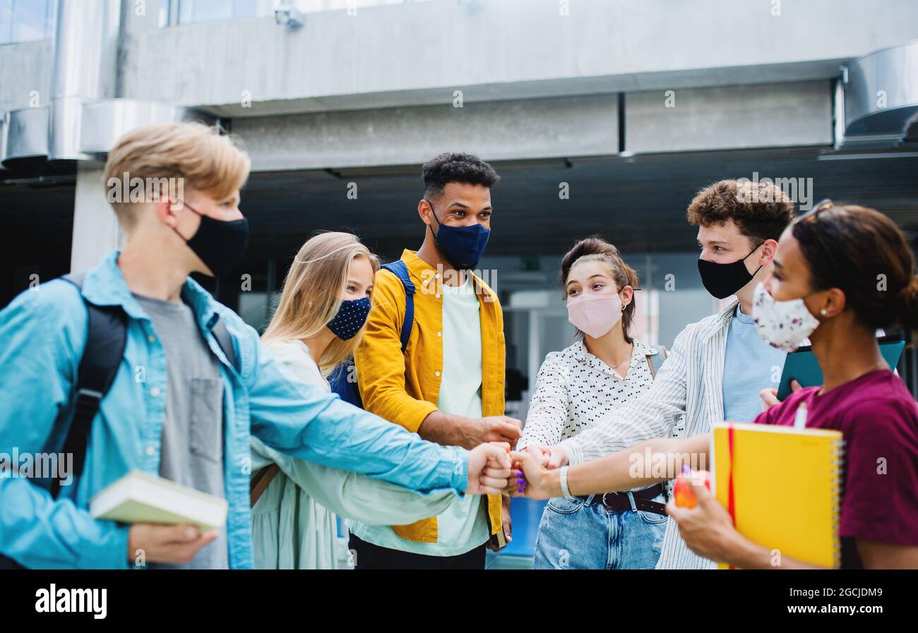 Studenten stehen und grüßen im Freien, Coronavirus und zurück zum normalen Konzept. Stockfoto