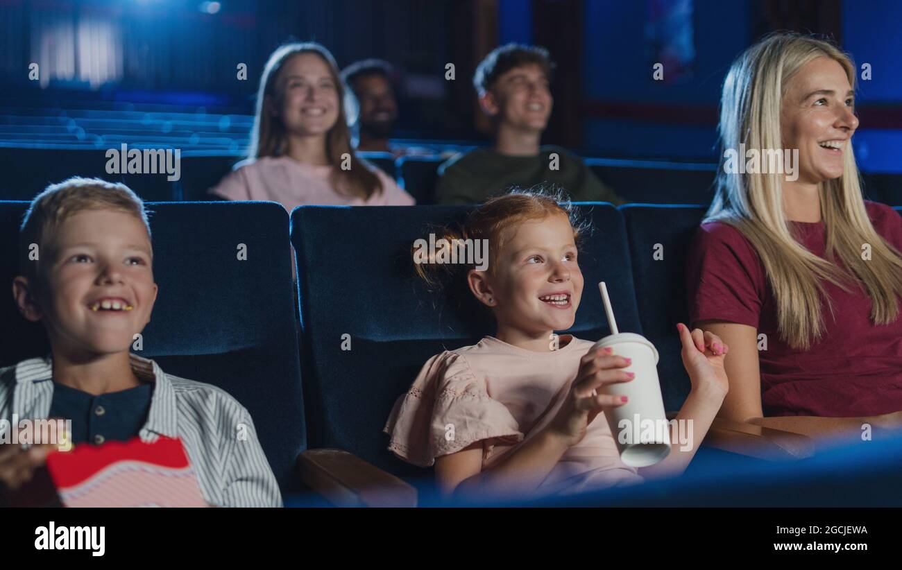 Mutter mit glücklichen kleinen Kindern im Kino, beim Film. Stockfoto