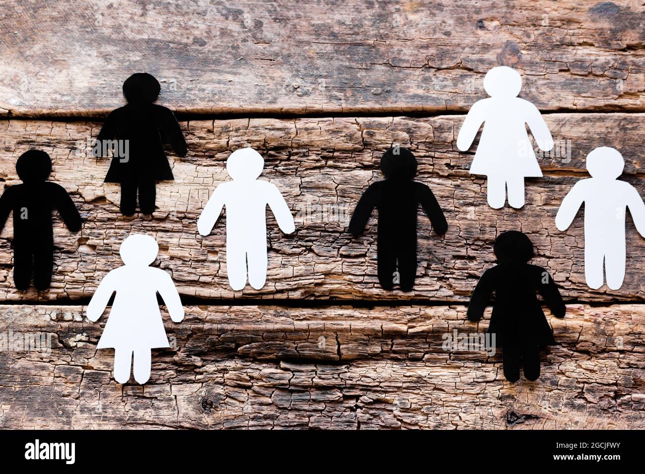 Gruppen von weißen und schwarzen Silhouetten auf hölzernen Hintergrund Anti-Rassismus-Konzept Stockfoto