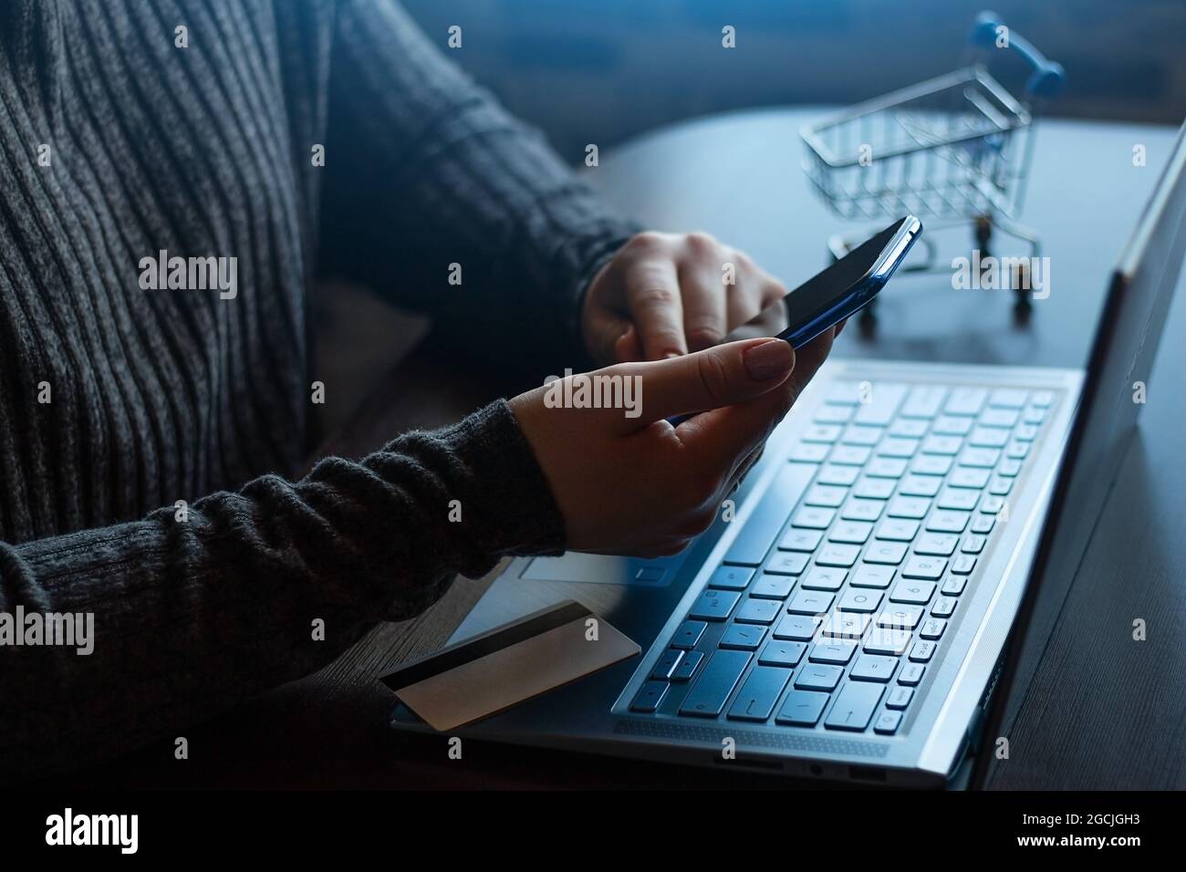 Halten Sie ein Smartphone auf dem Hintergrund eines Laptops und eine Bankkarte Online-Shopping, Zahlungskonzept Stockfoto