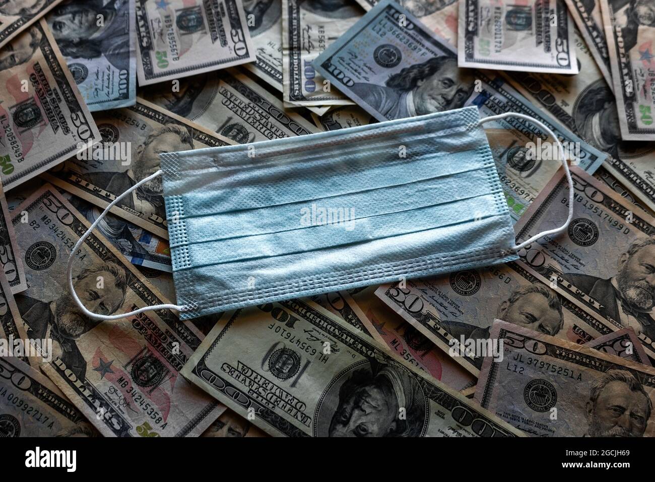 Medizinische Maske auf dem Hintergrund von Dollarscheinen, Konzeptkrise, Pandemie, Inflation Stockfoto