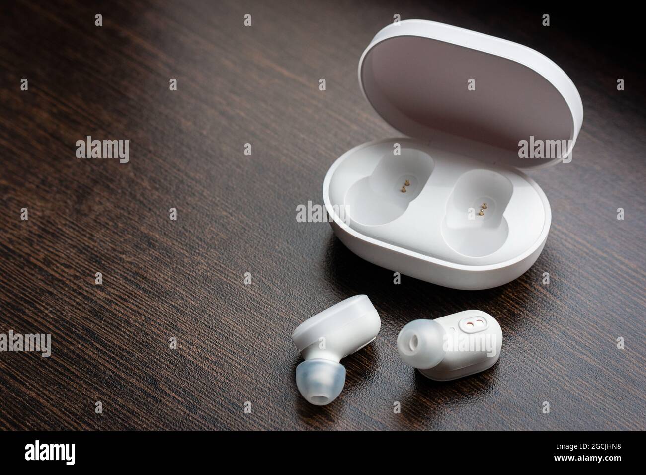Kabellose bluetooth-Kopfhörer und Ladegerät auf einem Holzhintergrund mit Platz für Text Stockfoto