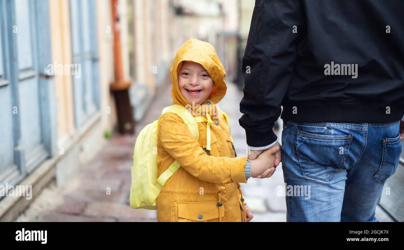 Happy Down-Syndrom Junge mit unkenntlichen Vater im Freien auf einem Spaziergang im Regen, Blick auf die Kamera. Stockfoto