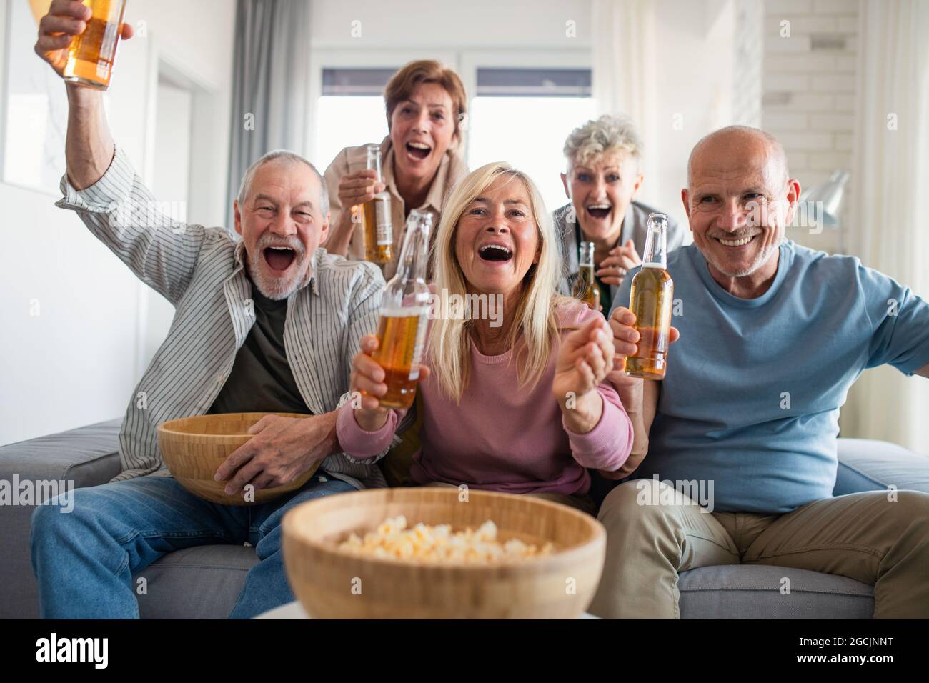Gruppe von älteren Freunden, die Filme in Innenräumen anschauen, feiern, gesellige Treffen und Spaß haben Konzept. Stockfoto