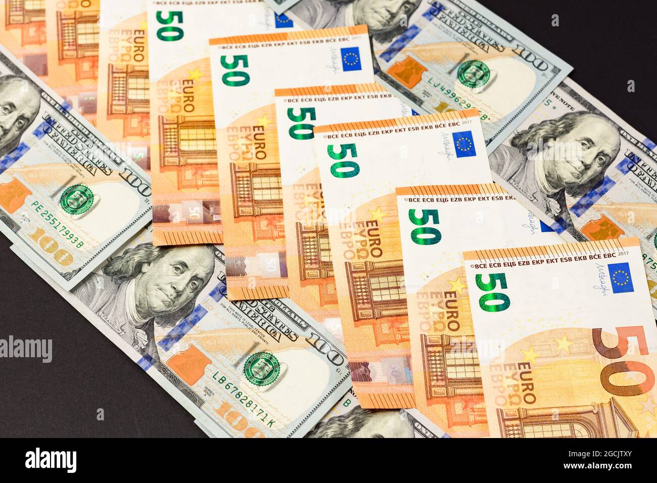 50 Euro und 100 Dollar liegen in Folge, Euro- und Dollarnoten auf schwarzem Hintergrund. Neu Stockfoto