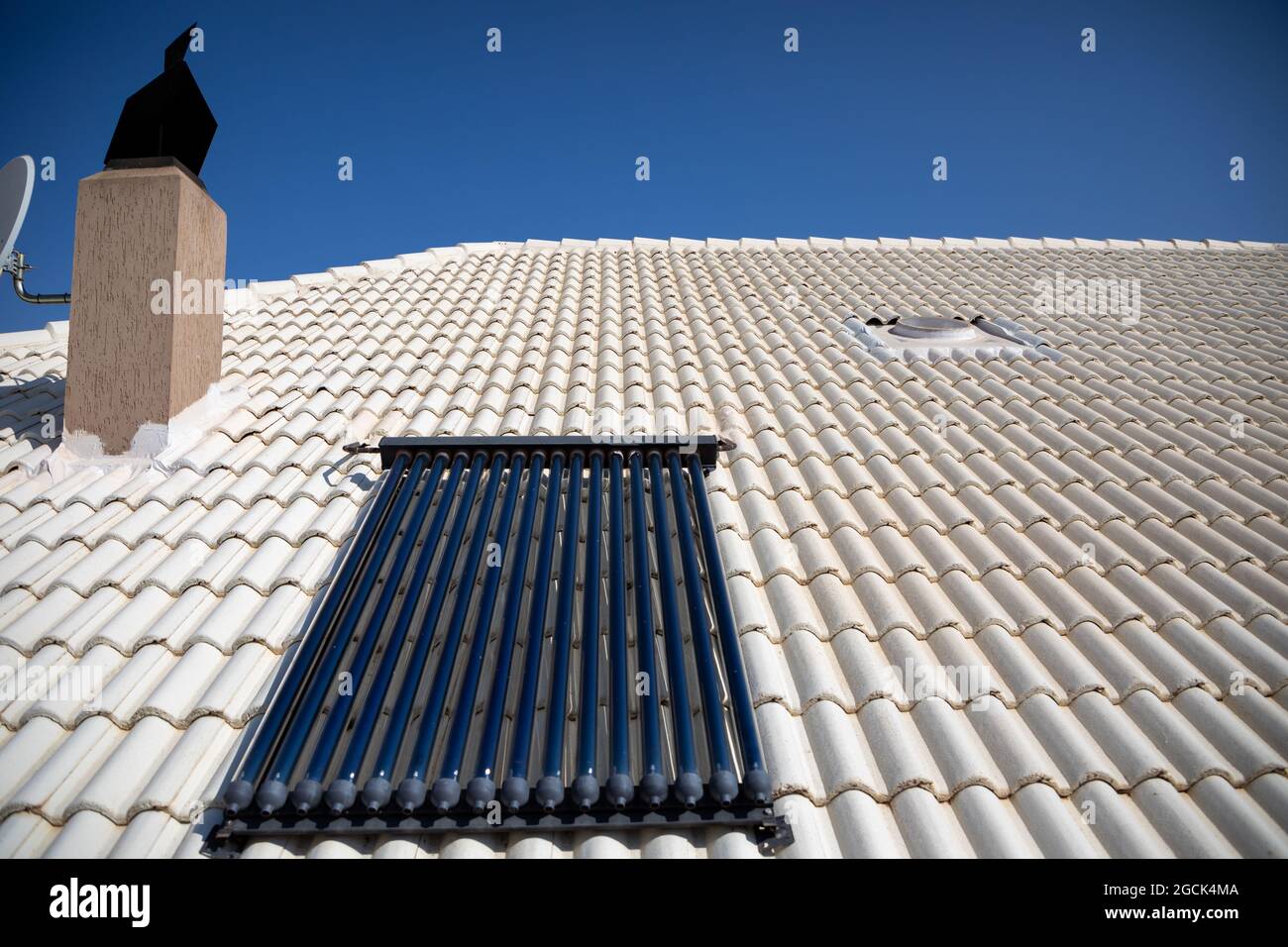 Das geflieste Dach ist weiß gestrichen, um die Hitze der Sonne abzulenken. Solar evakuierte Rohre, um Wasser ohne Energieverbrauch zu erhitzen. Stockfoto