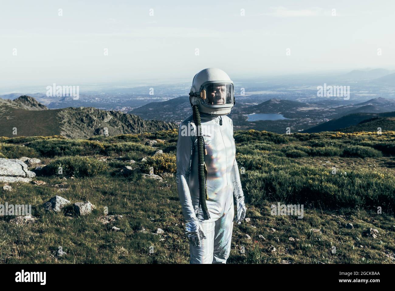 Männlicher Astronaut in Raumanzügen und Helm, der auf Gras und Steinen im Hochland steht Stockfoto