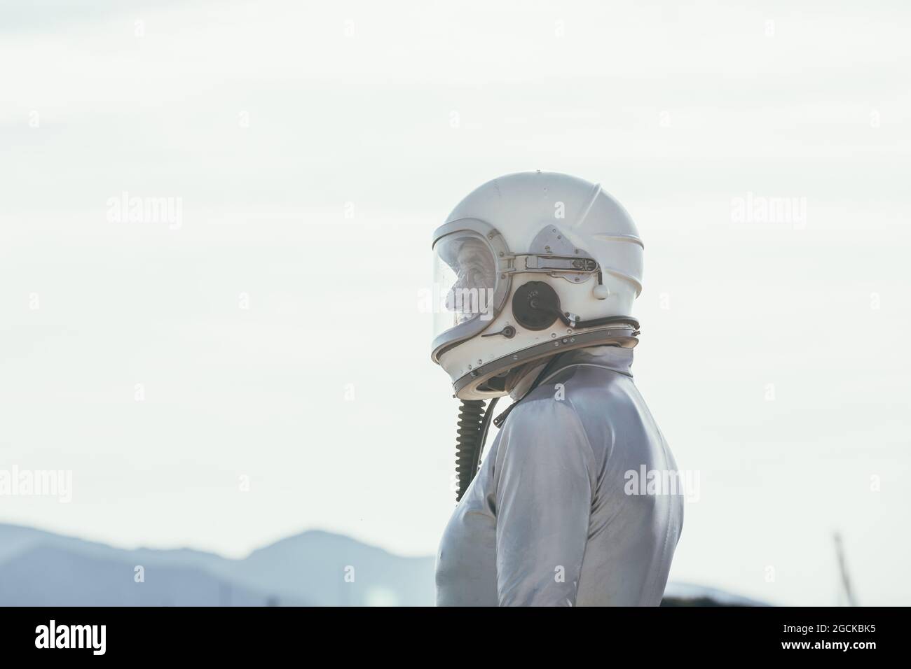 Seitenansicht auf Mann in Raumanzügen und Helm, der wegschaut, während er an sonnigen Tagen in der Natur auf dem Pfad steht Stockfoto