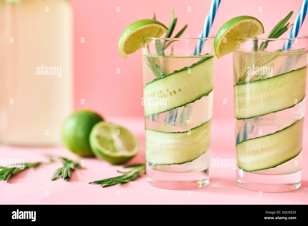 Kalte erfrischende Cocktails mit Limette, Gurke, Rosmarin und Eis im Glas auf rosafarbenem Hintergrund. Party, Sommerkonzept Stockfoto