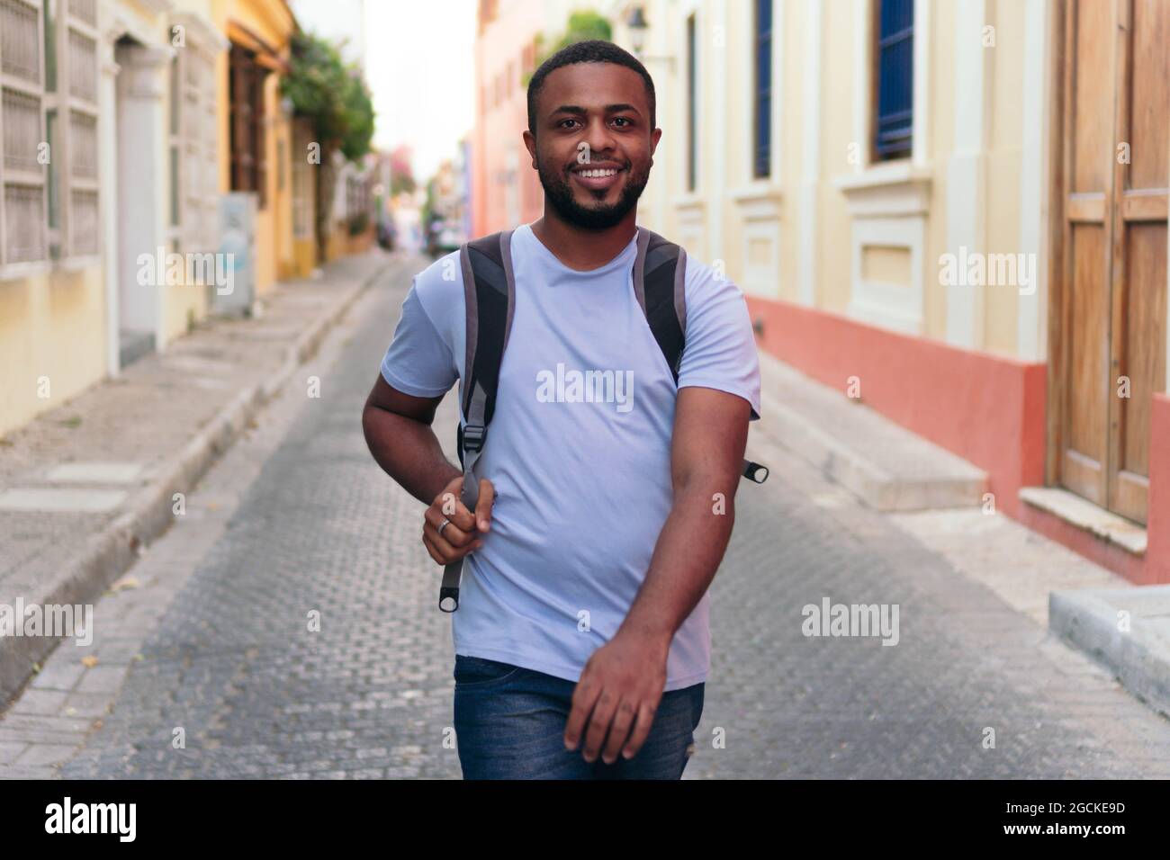 Schwarzer Mann, der Rucksack trägt, während er in der Stadt spazieren geht Stockfoto