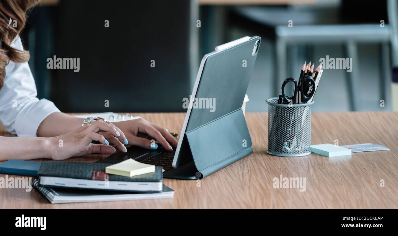Nahaufnahme der Geschäftsfrau, die die Tastatur auf dem digitalen Tablet eines Laptops tippt Stockfoto