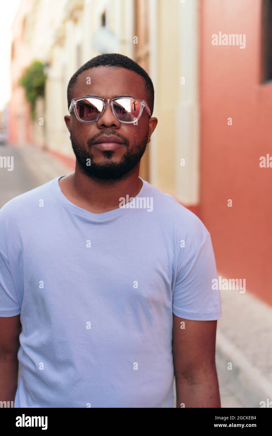 Porträt eines eleganten schwarzen Mannes, der mit einer Sonnenbrille im Freien unterwegs ist. Modischer schwarzer Mann auf der Straße. Stockfoto