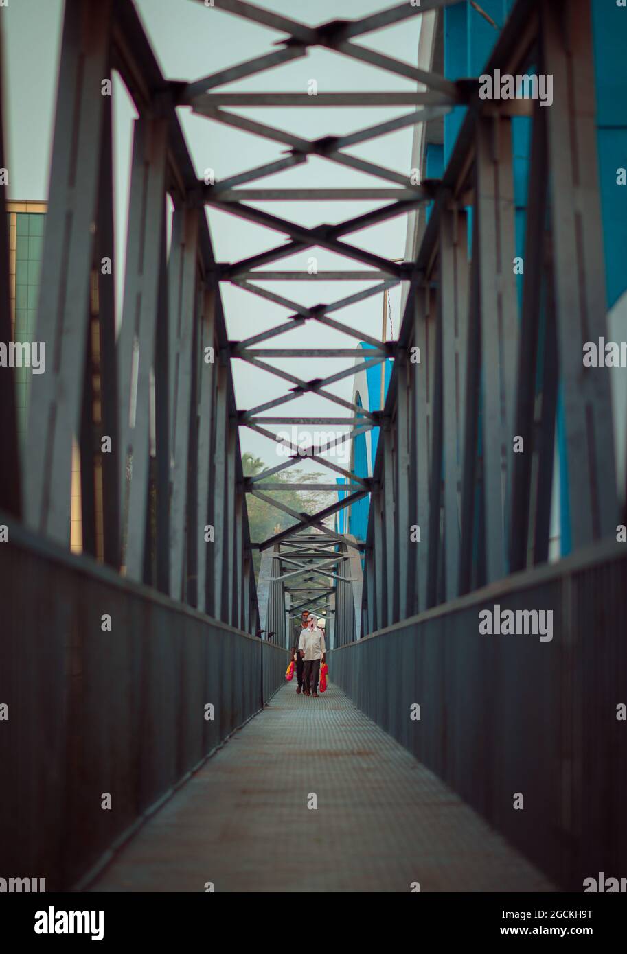 Männer gehen mit einer Tasche in der Hand durch eine Brücke zur Arbeit Stockfoto