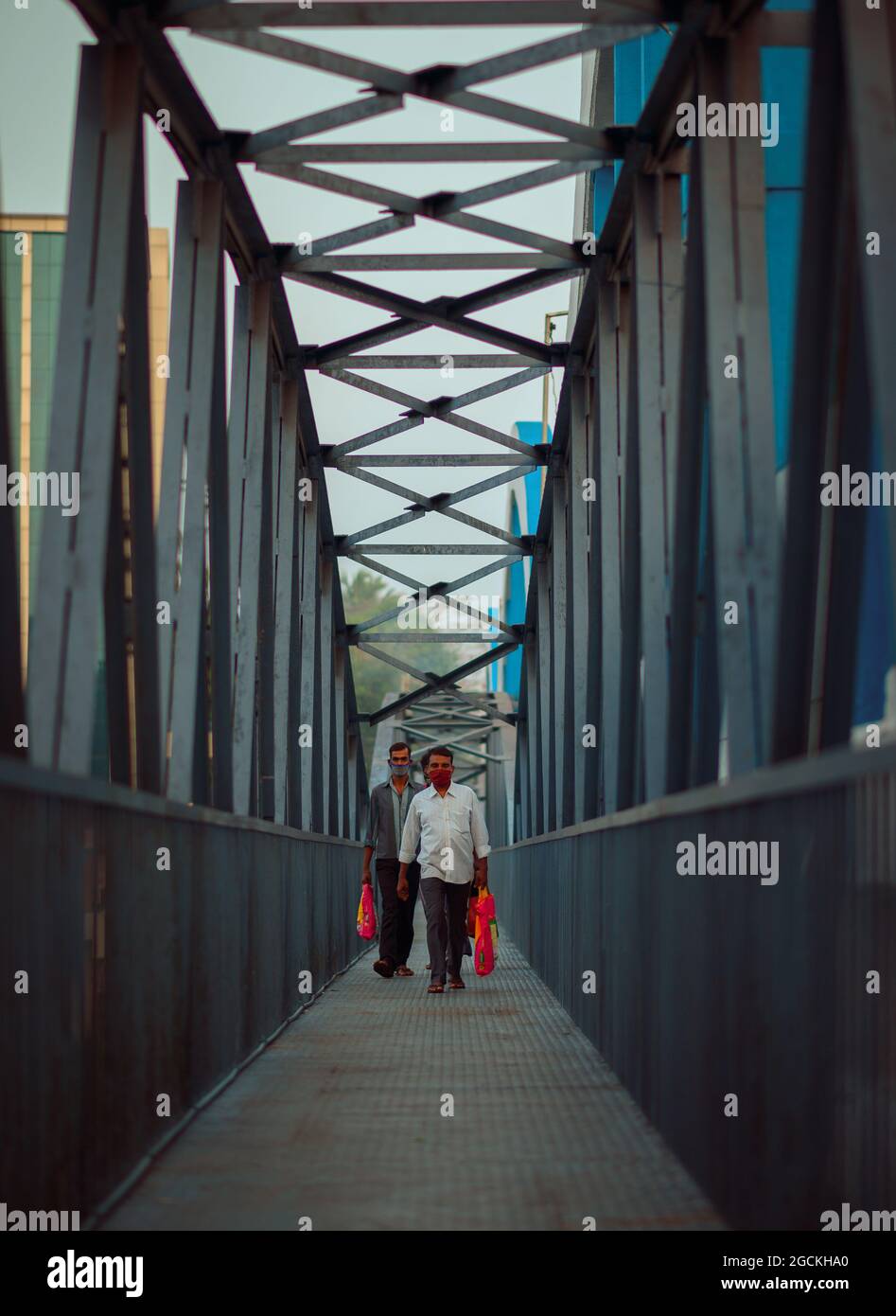 Männer gehen mit einer Tasche in der Hand durch eine Brücke zur Arbeit Stockfoto