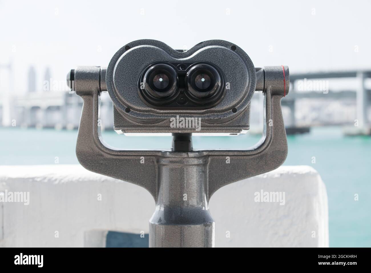Fernrohr, montiert auf einer rotierenden Basis am Flussufer einer modernen Stadt. Vorderansicht, Nahaufnahme mit selektivem Fokus Stockfoto