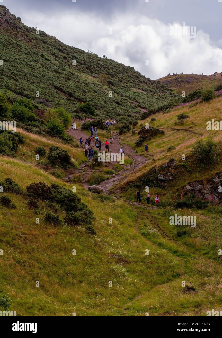 Gruppen von Menschen, die einen der Pfade in Arthur Seat in Edinburgh, Schottland, Großbritannien, hinaufgehen Stockfoto