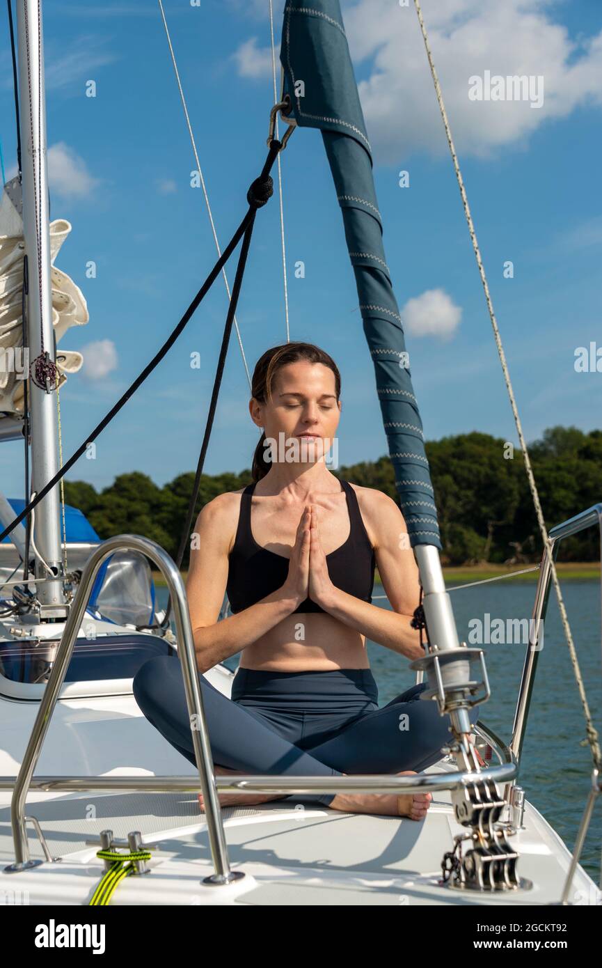 Friedliche junge Frau, die Yoga auf einer Yacht praktiziert Stockfoto