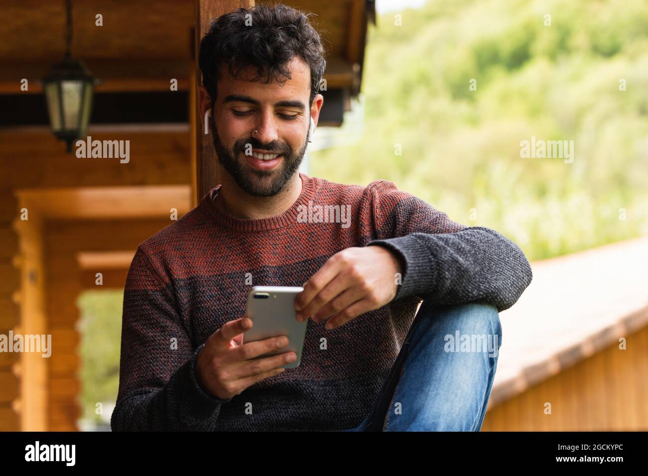 Rückansicht des entfernten gesichtslosen Mannes mit langen lockigen Haaren Trägt weißes Hemd, das auf einem sonnigen Hügel steht und die Weite bewundert Malerisches Tal mit ruhigen po Stockfoto