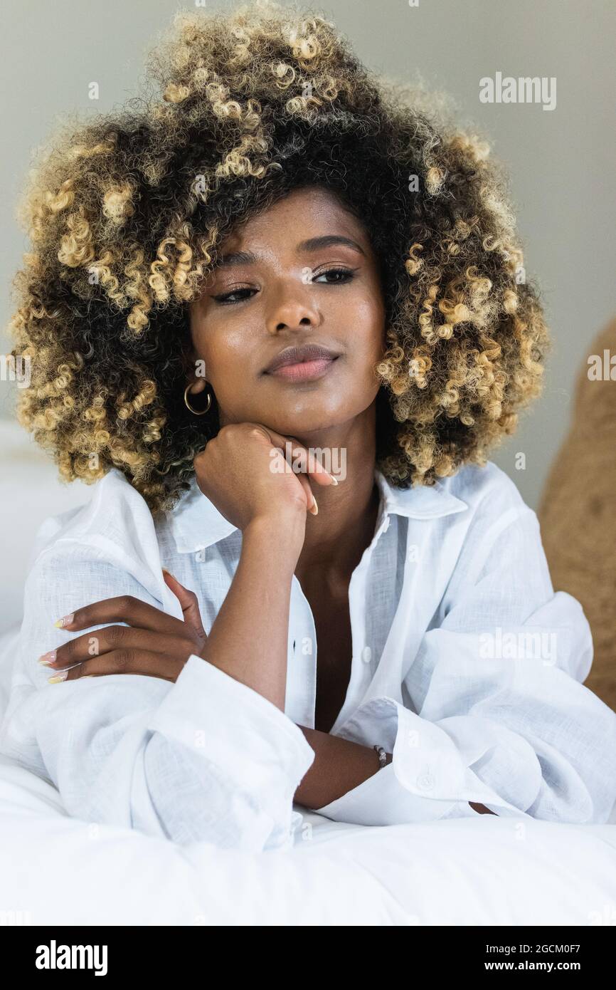 Attraktive afroamerikanische Frau, die sich auf dem Bett niederlegt und die Kamera anschaut Stockfoto