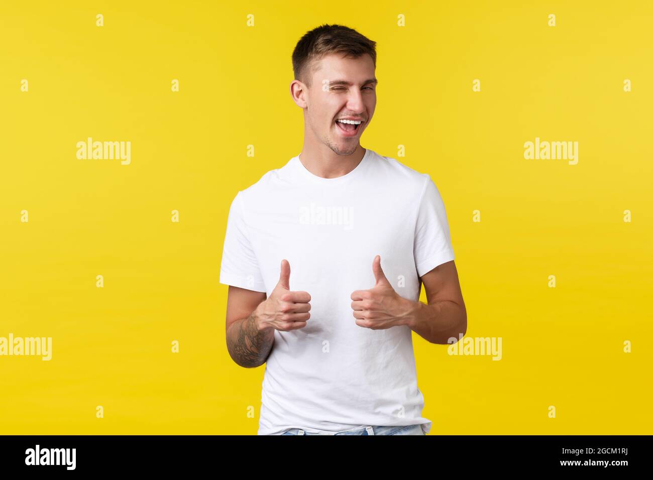 Lifestyle, Sommer und Menschen Emotionen Konzept. Frech zufrieden männlichen Kunden in einfachen weißen T-Shirt, zwinkernde und lächelnde ermutigen versuchen Stockfoto