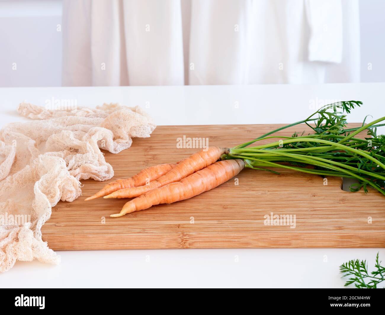 Drei orangefarbene Karotten liegen auf einem Schneidebrett. Nahaufnahme. Stockfoto