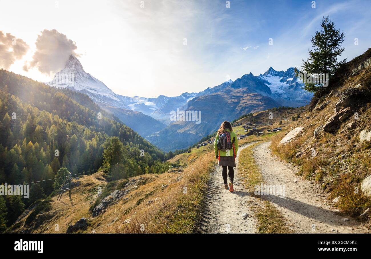 Junge Frau, die in der Nähe der Schweizer Kurstadt Zermatt auf einem Wanderweg in den Bergen spazierengeht Stockfoto