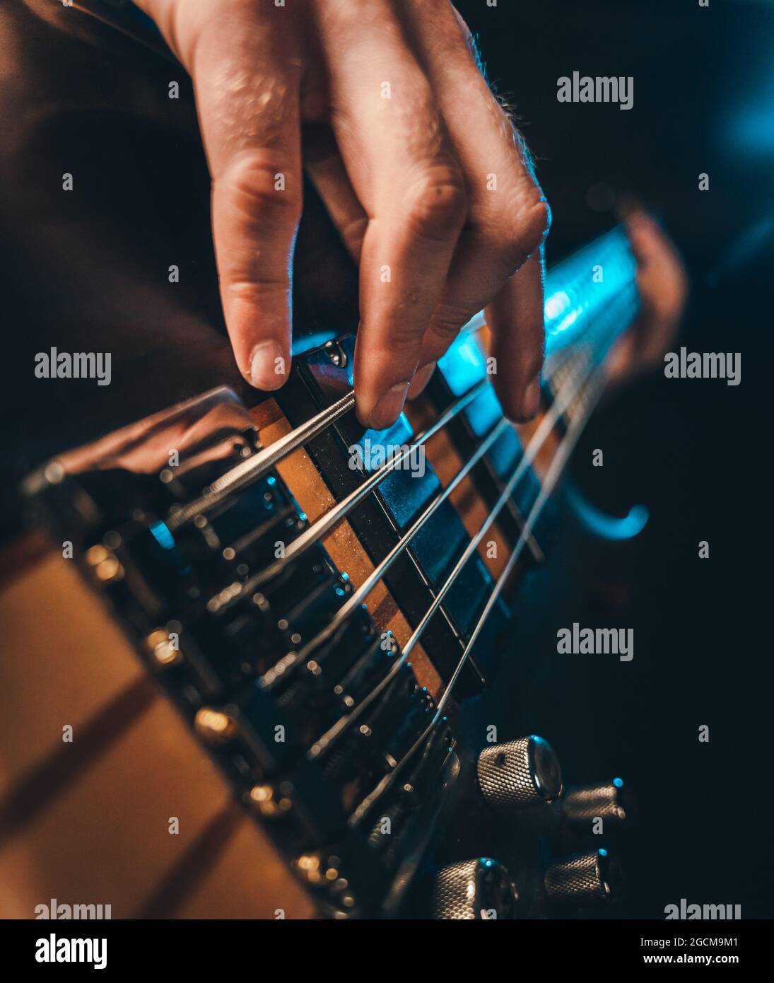 Nahaufnahme von männlichen Fingern, die 5-saitige E-Bass-Gitarre spielen Stockfoto