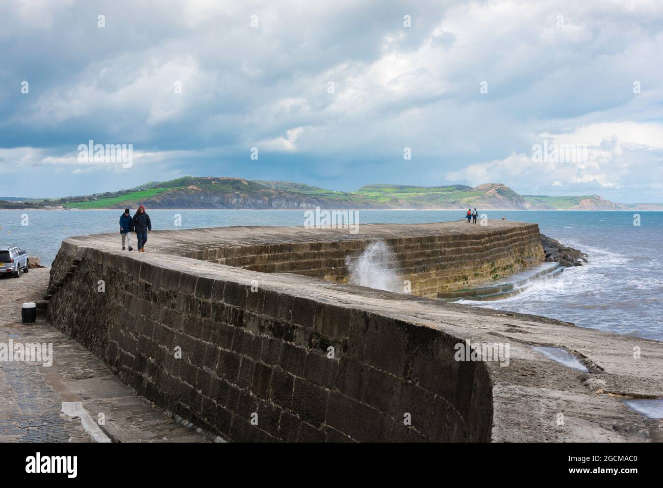 Dorset-Küste, Blick auf Menschen, die auf der Cob spazieren - die markante geschwungene Hafenmauer im Dorset-Ferienort Lyme Regis, England, Großbritannien Stockfoto
