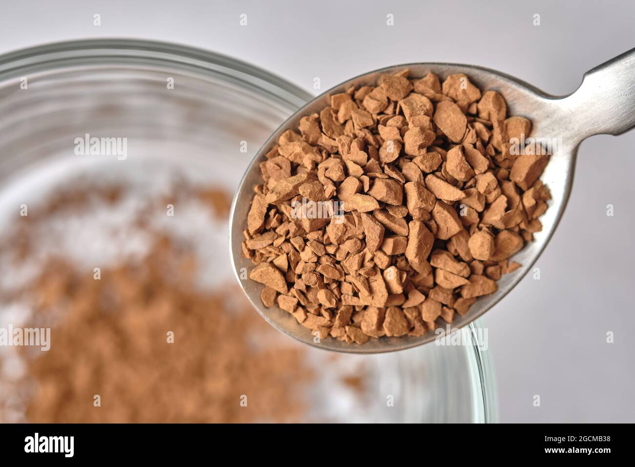 Nahaufnahme, gefrieren getrockneten Instant-Kaffee auf Teelöffel mit Glas-Kaffee-Tasse Hintergrund. Stockfoto